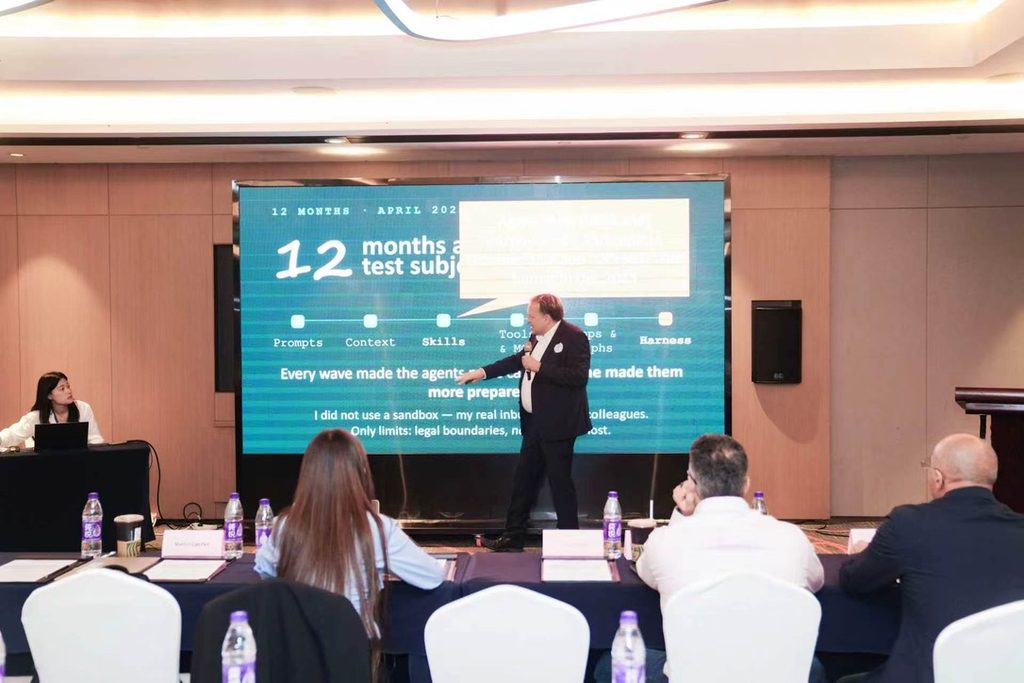 Showing Gaedke in front of the audience pointing on the slide "12 month with agents"